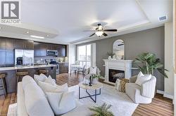 Living room with a glass covered fireplace, ceiling fan, light wood finished floors, and recessed lighting - 