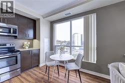 Kitchen featuring dark brown cabinetry, appliances with stainless steel finishes, tasteful backsplash, light stone countertops, and dark wood-type flooring - 