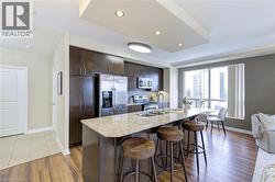Kitchen with dark brown cabinetry, stainless steel appliances, light stone countertops, a breakfast bar area, and recessed lighting - 