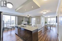 Kitchen featuring dark brown cabinetry, open floor plan, light stone countertops, stainless steel appliances, and a fireplace - 