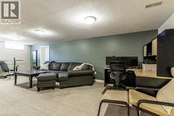 Large Rec Room/Living  area with a textured ceiling, a desk, and light colored carpet - 