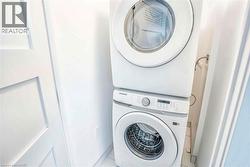 Washroom with stacked washer / drying machine and tile patterned floors - 