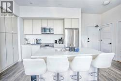 Kitchen with stainless steel appliances, light wood-type flooring, modern cabinets, and a kitchen island with sink - 