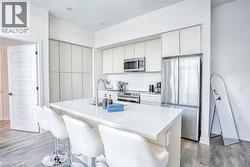 Kitchen featuring light countertops, stainless steel appliances, light wood-type flooring, and a breakfast bar area - 