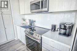 Kitchen featuring modern cabinets, stainless steel appliances, light wood finished floors, and light stone counters - 