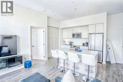 Kitchen with appliances with stainless steel finishes, a breakfast bar area, light wood finished floors, and a kitchen island with sink - 