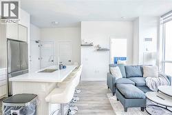 Kitchen featuring freestanding refrigerator, light wood-style flooring, a center island with sink, a breakfast bar area, and modern cabinets - 