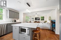 Kitchen with gray cabinets, healthy amount of natural light, appliances with stainless steel finishes, and a kitchen bar - 