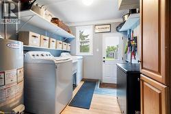 Laundry area featuring water heater, washing machine and dryer, and light wood finished floors - 