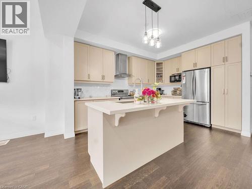 Kitchen with cream cabinets, stainless steel appliances, a kitchen island with sink, hanging light fixtures, and a kitchen bar - 30 Times Square Boulevard, Hamilton, ON - Indoor Photo Showing Kitchen