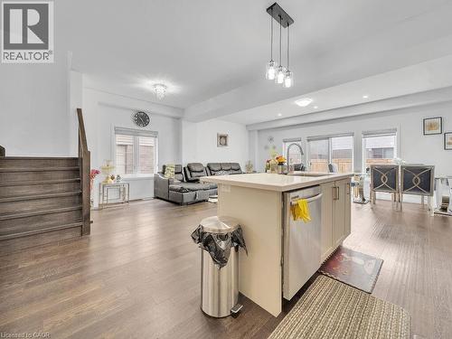 Kitchen with a center island with sink, open floor plan, hanging light fixtures, stainless steel dishwasher, and dark wood-style floors - 30 Times Square Boulevard, Hamilton, ON - Indoor