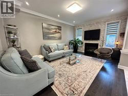 Living room with dark wood-style flooring, ornamental molding, a large fireplace, and recessed lighting - 