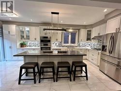 Kitchen with glass insert cabinets, a kitchen bar, appliances with stainless steel finishes, pendant lighting, and recessed lighting - 