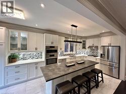 Kitchen with glass insert cabinets, stainless steel appliances, a breakfast bar, white cabinets, and recessed lighting - 