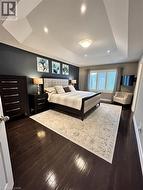 Bedroom featuring a tray ceiling, dark wood-style flooring, and recessed lighting - 