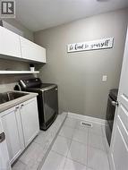 Laundry room with cabinet space, washer and dryer, and light tile patterned floors - 