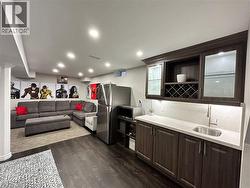 Kitchen with dark brown cabinetry, stainless steel appliances, open shelves, light stone counters, and dark wood-type flooring - 