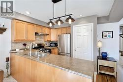 Kitchen with decorative backsplash, stainless steel appliances, hanging light fixtures, light countertops, and recessed lighting - 