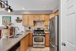 Kitchen with stainless steel appliances, a textured ceiling, decorative backsplash, light countertops, and light tile patterned flooring - 