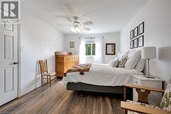Bedroom with wood finished floors, a ceiling fan, and a textured ceiling - 