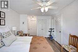 Bedroom with dark wood-type flooring, multiple closets, and ceiling fan - 