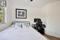 Bedroom featuring dark wood-style floors, a ceiling fan, and an office area - 