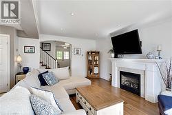 Living area with wood finished floors, arched walkways, stairs, ornamental molding, and a fireplace - 