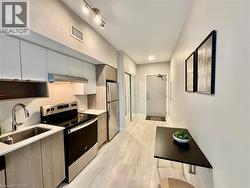 Kitchen featuring Stainless Steel appliances, modern 2-tone cabinets with soft-close doors, under cabinet Range- hood, with light & fan, light-coloured laminate flooring - 