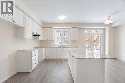 Kitchen with sink, white cabinetry, light stone countertops, light hardwood / wood-style floors, and a kitchen island - 109 Molozzi Street, Erin, ON - Indoor Photo Showing Kitchen With Upgraded Kitchen
