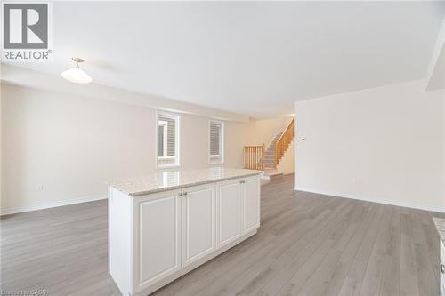 Kitchen featuring a center island, white cabinets, light stone counters, and light hardwood / wood-style flooring - 109 Molozzi Street, Erin, ON - Indoor