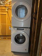 Laundry room with stacked washer / drying machine and concrete flooring - 