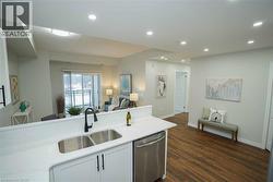 Kitchen with white cabinets, open floor plan, dishwasher, light stone countertops, and dark wood-style flooring - 