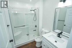 Bathroom with a shower stall, vanity, and dark wood finished floors - 