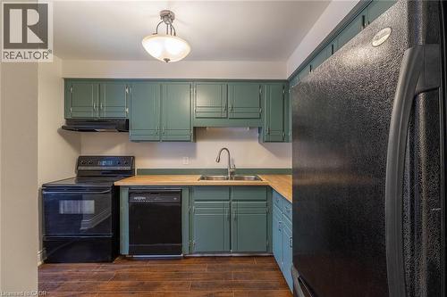 Kitchen featuring black appliances, light countertops, under cabinet range hood, dark wood finished floors, and green cabinetry - 58 Romy Crescent, Thorold, ON - Indoor Photo Showing Kitchen With Double Sink