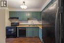 Kitchen featuring black appliances, light countertops, under cabinet range hood, dark wood finished floors, and green cabinetry - 58 Romy Crescent, Thorold, ON  - Indoor Photo Showing Kitchen With Double Sink 