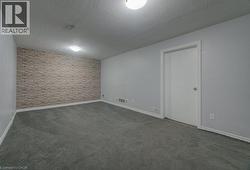 Empty room with dark carpet, a textured ceiling, and an accent wall - 