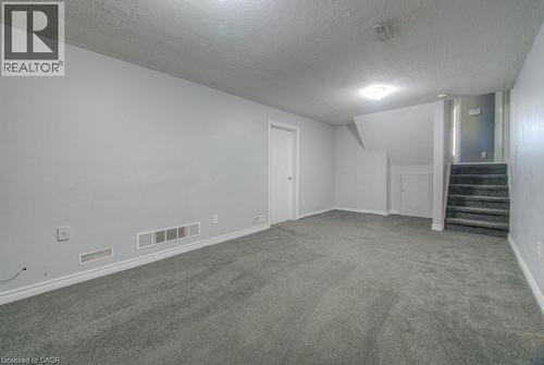 Finished basement with a textured ceiling, stairs, and carpet floors - 46 Guerin Avenue, Kitchener, ON - Indoor Photo Showing Other Room