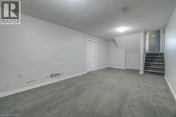 Finished basement with a textured ceiling, stairs, and carpet floors - 