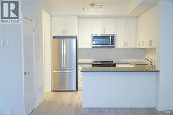 Kitchen featuring stainless steel appliances, white cabinetry, light wood-type flooring, and a peninsula - 