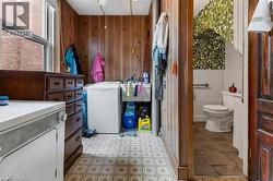 Bathroom featuring washer / clothes dryer, vanity, wooden walls, and light flooring - 