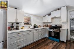 Kitchen featuring appliances with stainless steel finishes, white cabinetry, decorative backsplash, and vaulted ceiling - 