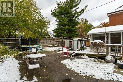 Snow covered patio featuring a trampoline, a patio area, a fenced backyard, a deck, and a storage unit - 193 Locke Street N, Hamilton, ON - Outdoor