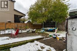 Fenced backyard featuring a trampoline, a patio, and a wooden deck - 