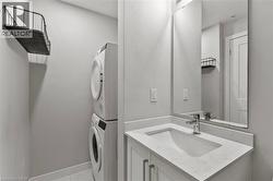 Bathroom with vanity, stacked washing machine and dryer, and light marble finish flooring - 