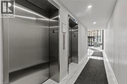 Corridor featuring elevator, light marble finish flooring, recessed lighting, a wall of windows, and a textured wall - 