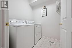 Laundry area with light tile patterned floors and washing machine and dryer - 