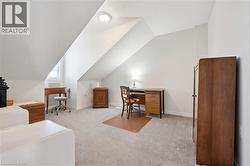 Office space with light colored carpet, vaulted ceiling, and a textured ceiling - 