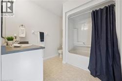 Bathroom featuring shower / bathtub combination with curtain, vanity, and light floors - 