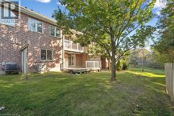 Back of house featuring a balcony, brick siding, a yard, and a wooden deck - 