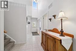 Foyer featuring light tile patterned floors, a towering ceiling, and stairs - 